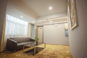 A hotel room with a sofa, a coffee table, a potted plant, and a patterned carpet. - Rujia Pebble Hotel (Baoying Anyi East Road, Baoying Yangzhou) (Baoying)