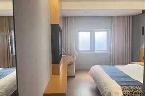 Une chambre d’hôtel avec deux lits, un bureau et une fenêtre avec des rideaux.