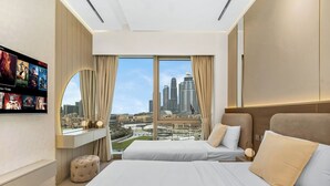 Een hotelkamer met een groot bed, een aan de muur bevestigde televisie en uitzicht op de stadsgezichten.
