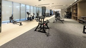 Un gimnasio moderno con máquinas de cardio, equipo de levantamiento de pesas y un espejo grande.