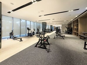 Un gimnasio moderno con máquinas de cardio, equipo de levantamiento de pesas y un espejo grande.