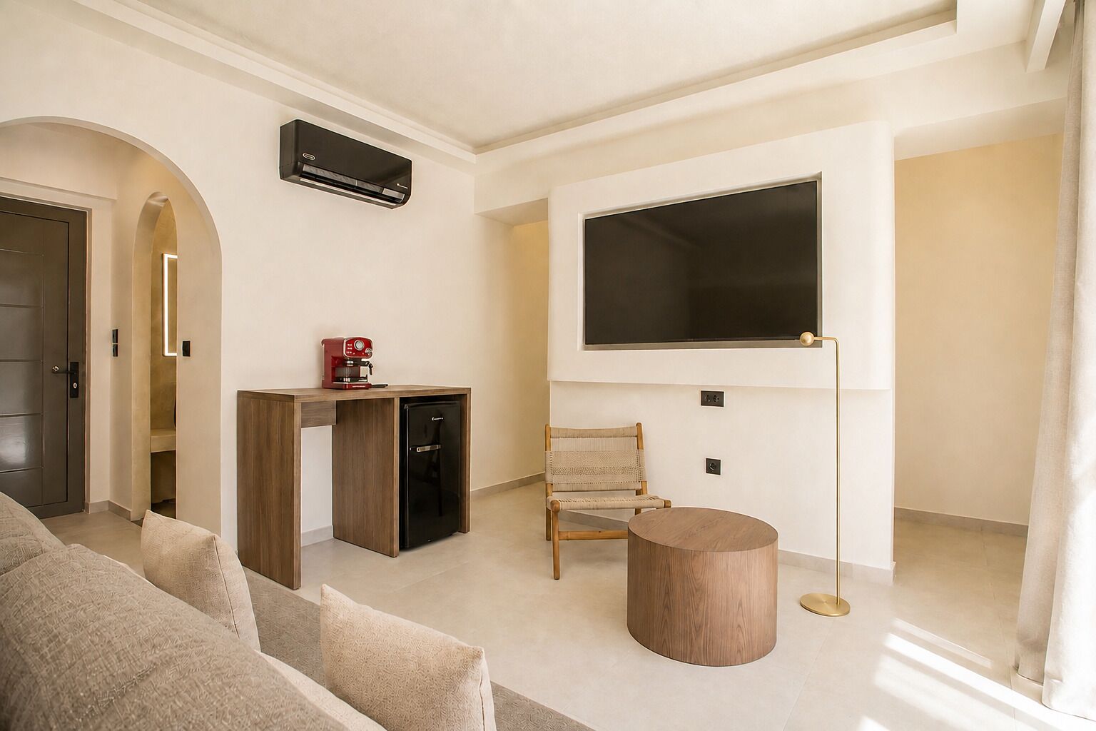 Un salon moderne comprenant un canapé, une table basse, un téléviseur fixé au mur et une petite table d’appoint.