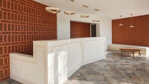Zona de recepción con un mostrador blanco, un área de descanso con un banco y una pared con diseño.