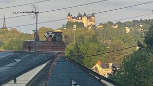 Uitzicht op een kasteel op een heuvel, met een kerk op de voorgrond.