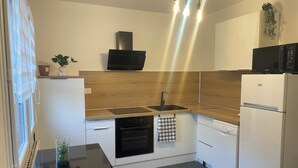 Een moderne keuken met een zwart fornuis, witte kasten, een zwarte magnetron en een witte koelkast.