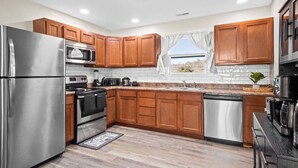 A modern kitchen with wooden cabinets, stainless steel appliances, and a window with a view.