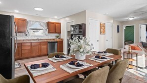 A modern kitchen with wooden cabinets, a built-in oven, and a dining area with a wooden table set for four.
