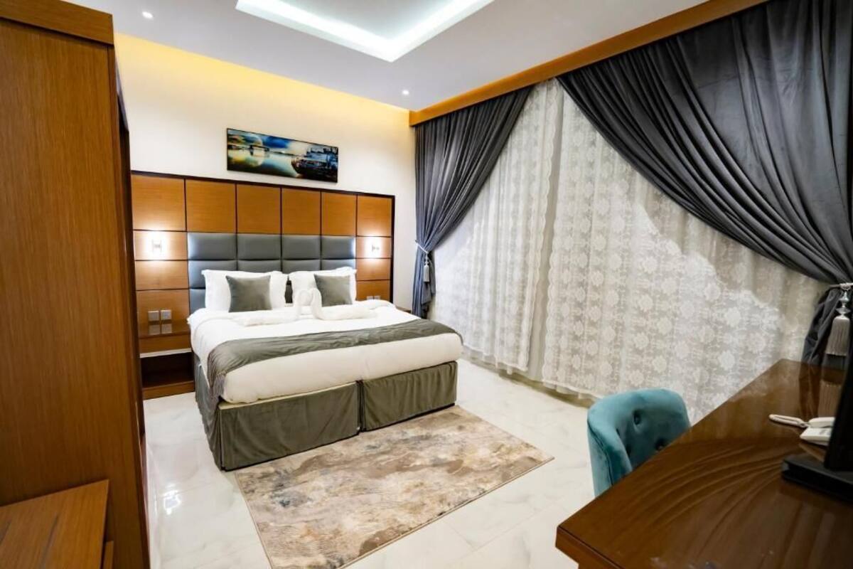 A modern bedroom with a large bed, a desk, and a chair.