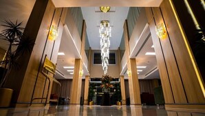 A spacious lobby with a reflective floor, a central chandelier, and wooden paneling on the walls. - Grand Season 3 (Al Khobar)
