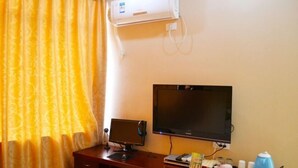 Una habitación de hotel con escritorio, dos monitores, aire acondicionado y hervidor.