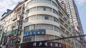 Un edificio de varios pisos con diversos comercios en la planta baja, incluyendo una agencia de alquiler de coches y un hotel.