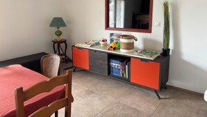 Een kamer met een bed, een bureau met lamp, een stoel, een boekenkast en een potplant.
