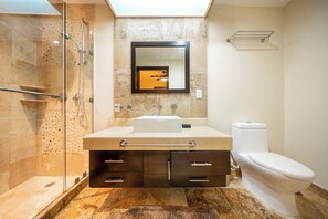 Une salle de bain moderne avec une douche à parois de verre, un lavabo avec un miroir au-dessus et des toilettes.