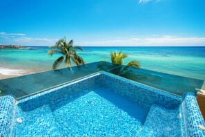 Une piscine d’un bleu éclatant, bordée de verre, qui offre une vue imprenable sur la plage et l’océan.