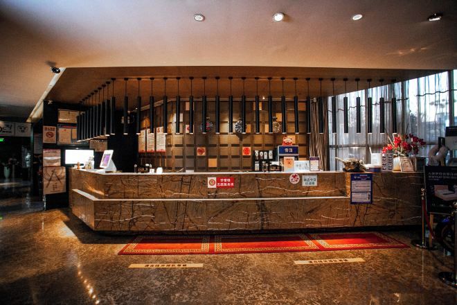 A hotel reception area with a marble counter, a large window, and a red carpet.