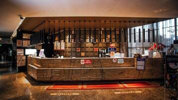 A hotel reception area with a marble counter, a large window, and a red carpet.