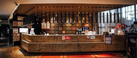 A hotel reception area with a marble counter, a large window, and a red carpet.