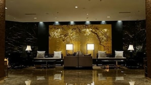 A lobby with a marble floor, two sofas with lamps, and a wall with a tree mural. - Tangshan Magnolia Business Hotel (Convention Center University Road) (Tangshan)