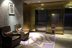 Un hall d’entrée avec deux ascenseurs, un comptoir de réception et un tapis à motifs.