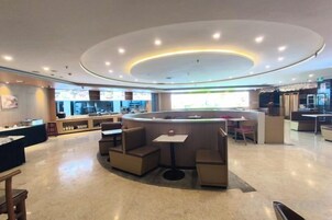 Un interior moderno con una zona de estar central, una barra y vista a la cocina.
