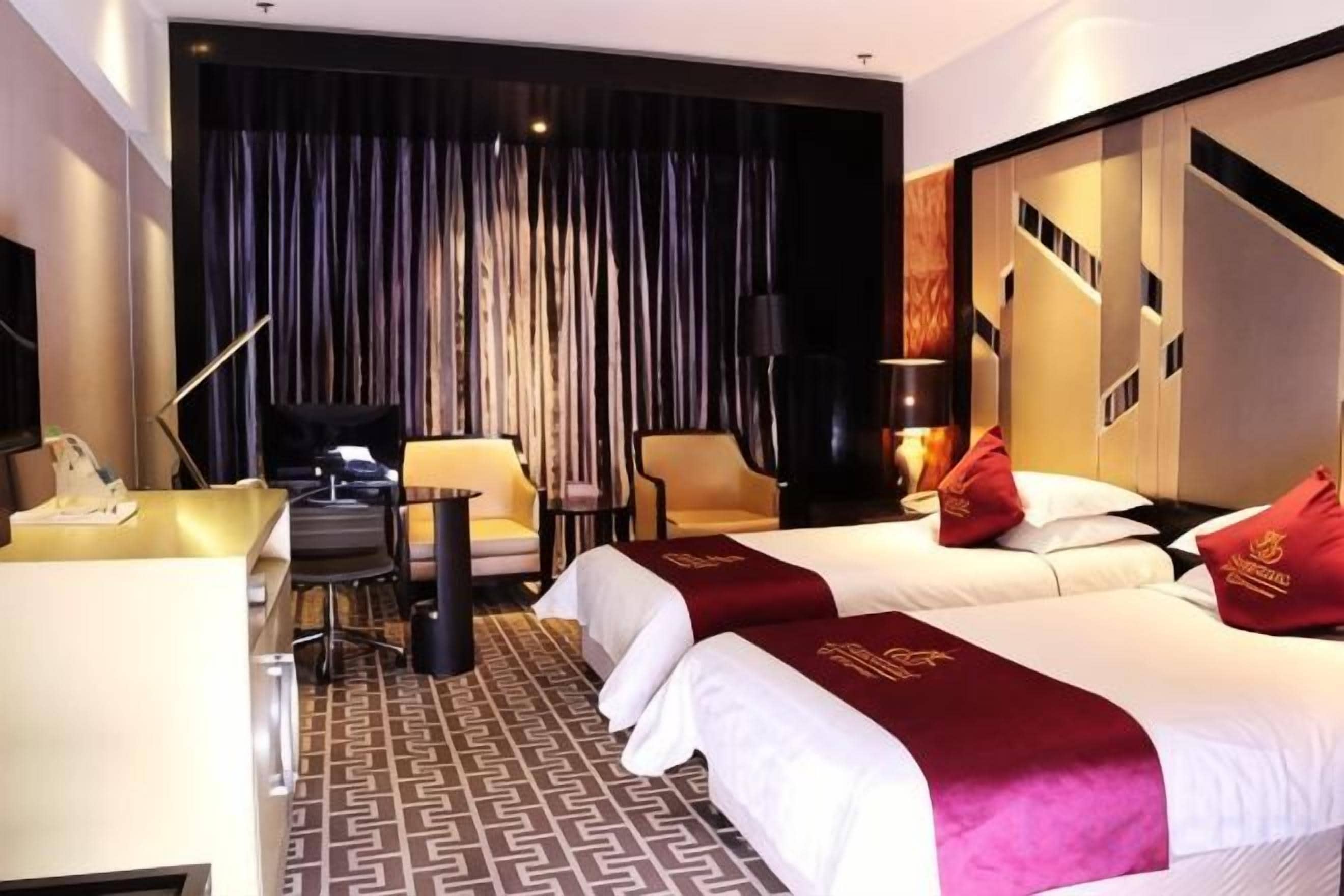Habitación de hotel con dos camas, un escritorio, una silla y un ventanal con cortinas.