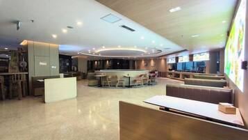 A modern hotel lobby with a central bar area, seating arrangements, and a reception desk.