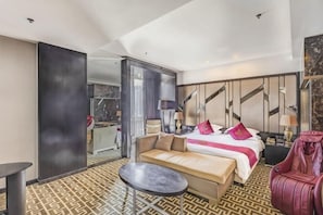Una habitación de hotel con cama, sofá, una mesita y una silla.