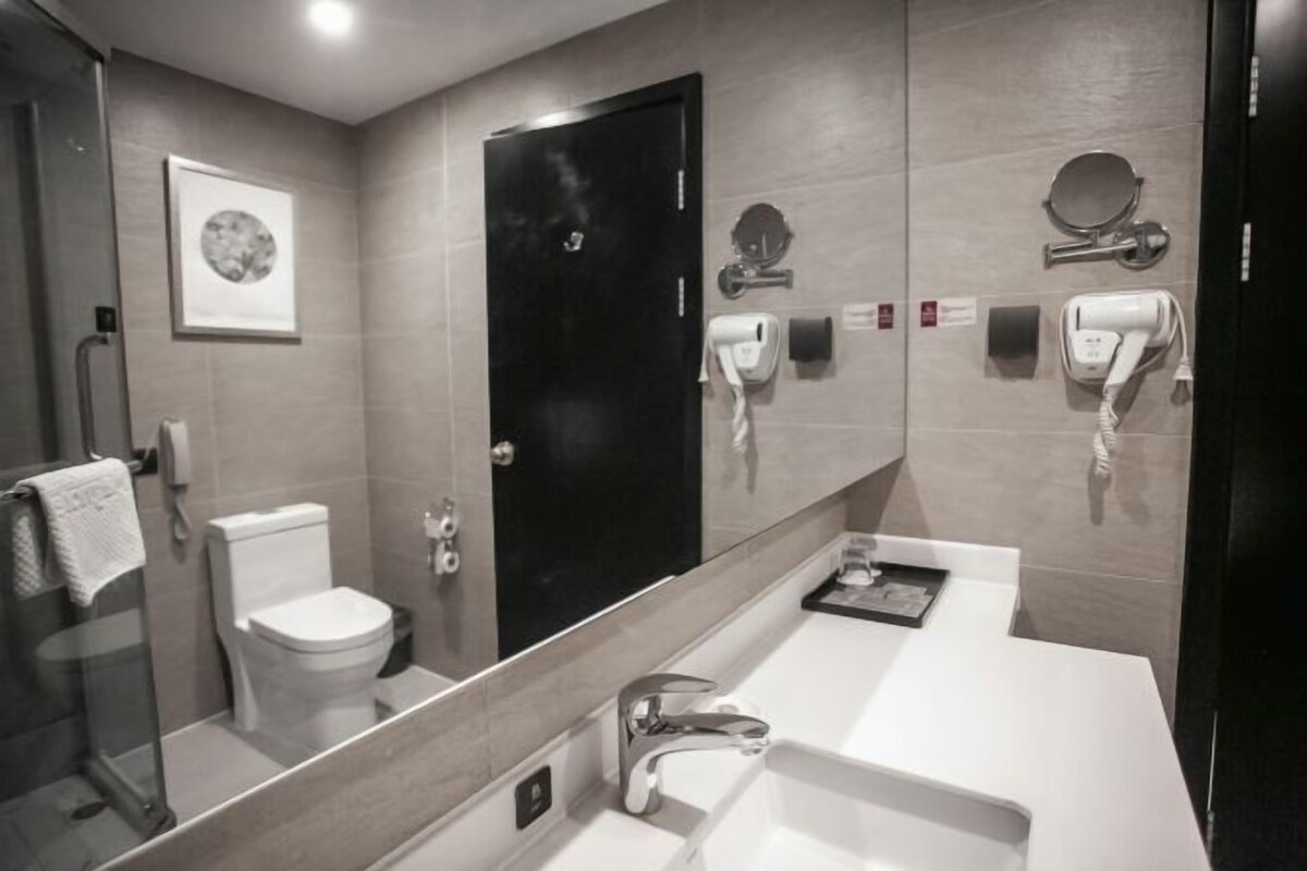 Uma casa de banho moderna com sanita, lavatório e espelho grande.