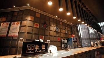 A hotel reception area with a marble counter, a cash register, and a wall with various signs and clocks.