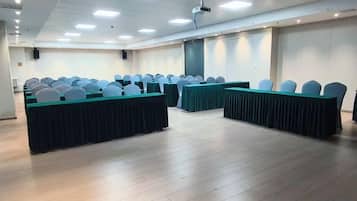 A conference room with rows of tables and chairs, a projector, and a large screen.