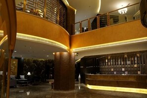 A lobby with a curved reception desk, a staircase, and a seating area. - Tangshan Magnolia Business Hotel (Convention Center University Road) (Tangshan)