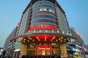 Un hotel de varios pisos con un llamativo letrero rojo en la entrada.