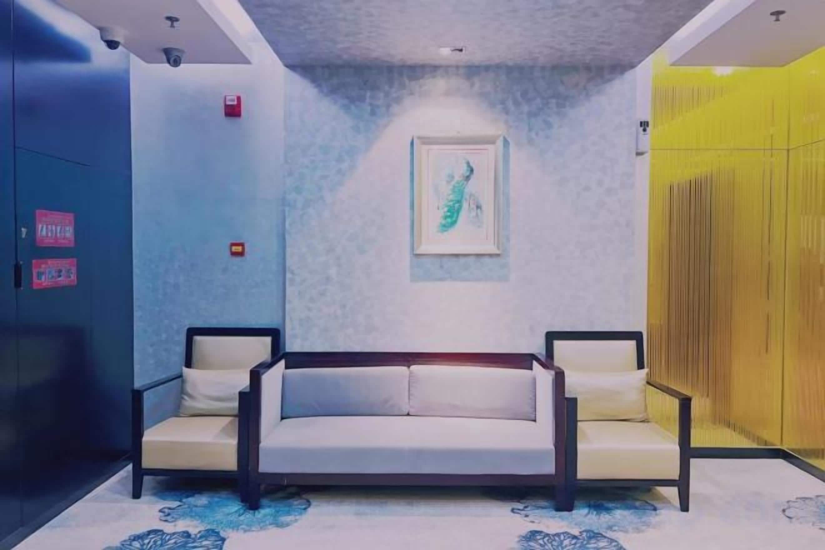 A hotel lobby with a sofa, a framed artwork on the wall, and a yellow partition.