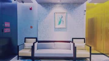 A hotel lobby with a sofa, a framed artwork on the wall, and a yellow partition.