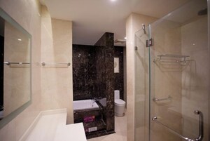 Un baño moderno con cabina de ducha de vidrio, una bañera blanca y un inodoro.