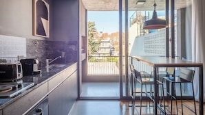Une cuisine moderne dotée d’une grande fenêtre, d’un coin repas avec des chaises et offrant une vue sur le paysage urbain.