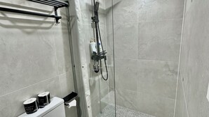 Een moderne badkamer met een douchecabine, een wit toilet en een handdoekrek.