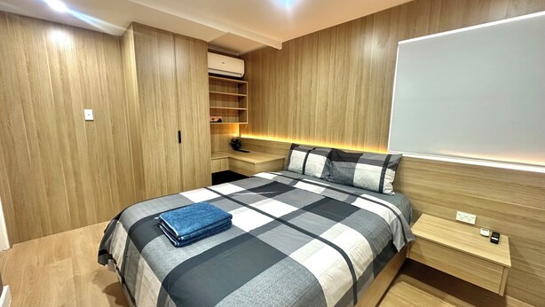 Een slaapkamer met een bed, nachtkastjes, een kledingkast en inbouwverlichting.