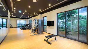 A gym with exercise equipment, large windows, and a television. - Serene Hideaway w Top Facilities in Creek Beach (Dubai)