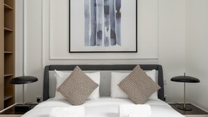 A neatly made bed with white linens, two decorative pillows, and two bedside lamps. - Serene Hideaway w Top Facilities in Creek Beach (Dubai)