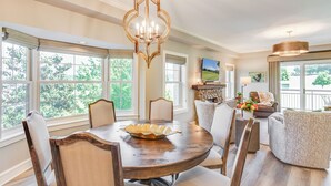 A dining room with a wooden table, chairs, and a chandelier.
