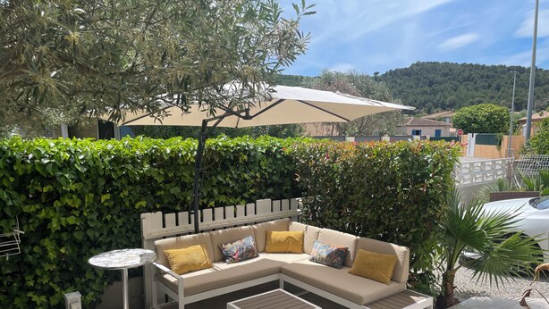 An outdoor seating area with a sofa, two side tables, and a large umbrella. - Luxury villa (Armissan)