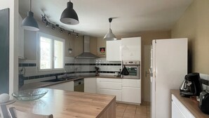 A modern kitchen with white cabinets, a wooden island, and pendant lighting. - Luxury villa (Armissan)