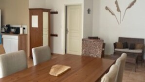 A spacious living area with a wooden dining table, comfortable seating, and a kitchen in the background. - Luxury villa (Armissan)