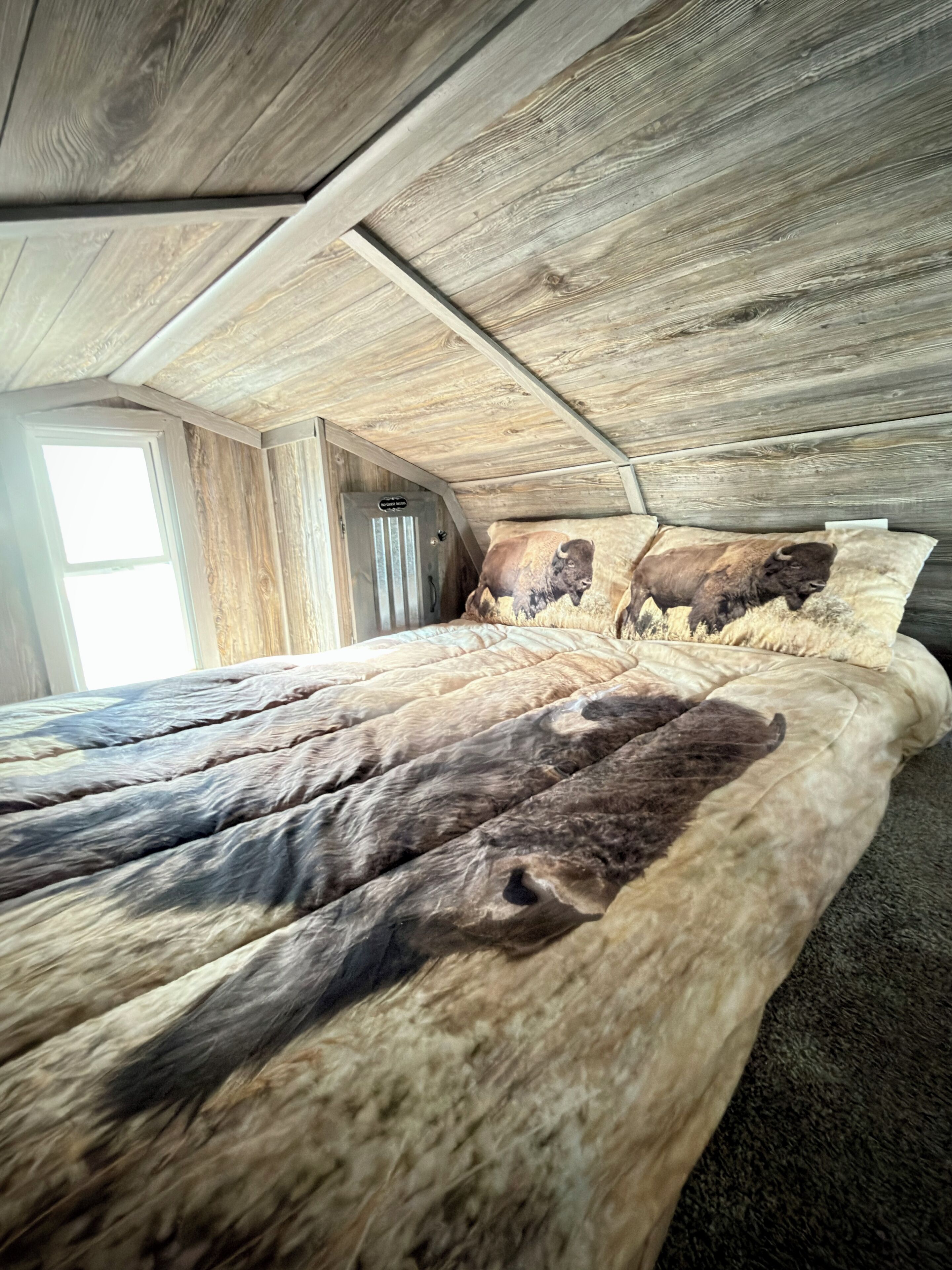 A bedroom with a sloped ceiling and wooden paneling.