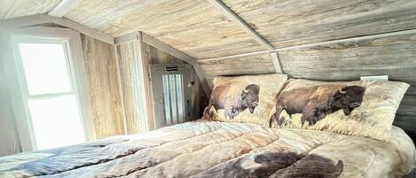 A bedroom with a sloped ceiling and wooden paneling.
