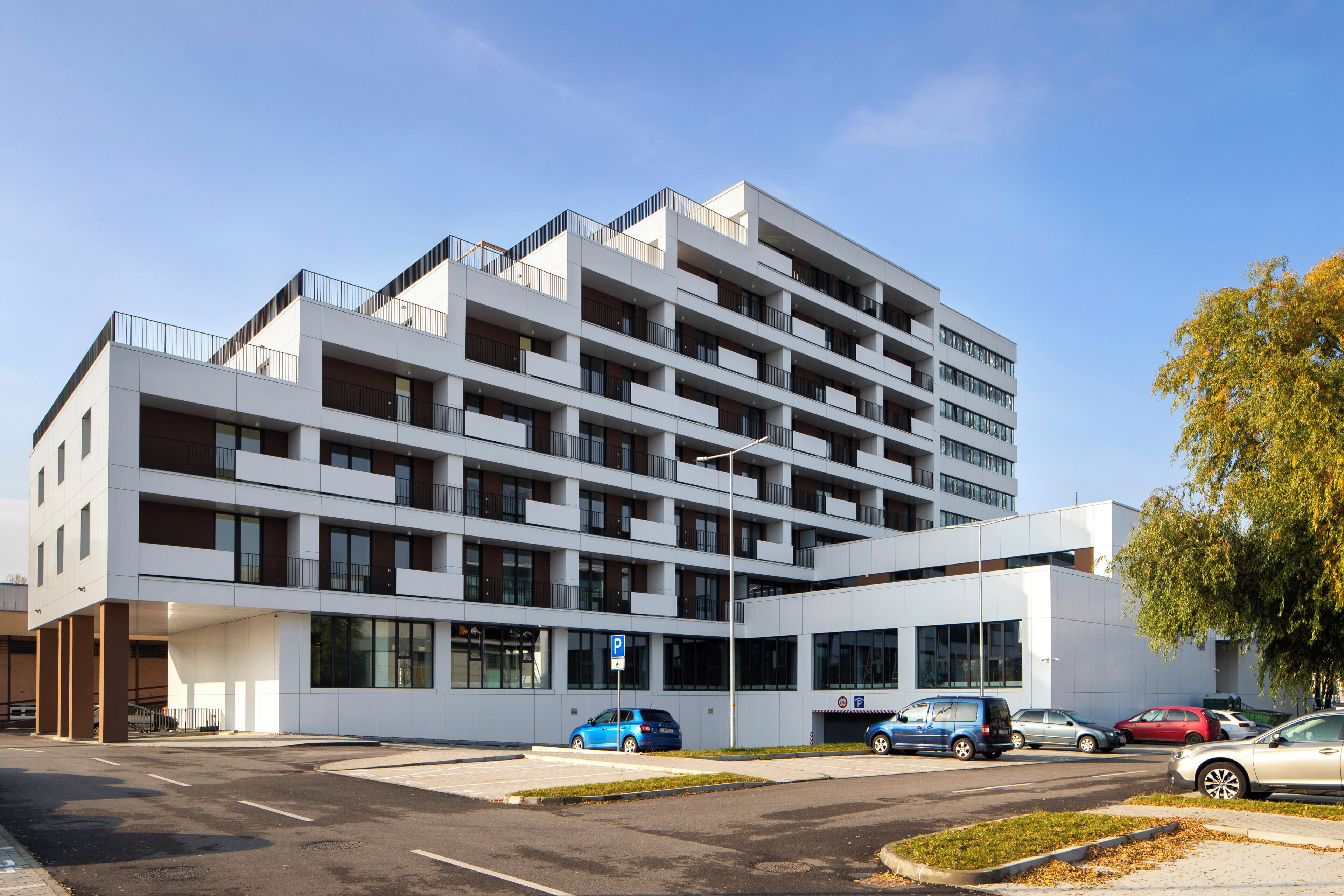 Un immeuble à plusieurs étages doté d’une architecture moderne, avec des balcons et de grandes fenêtres.