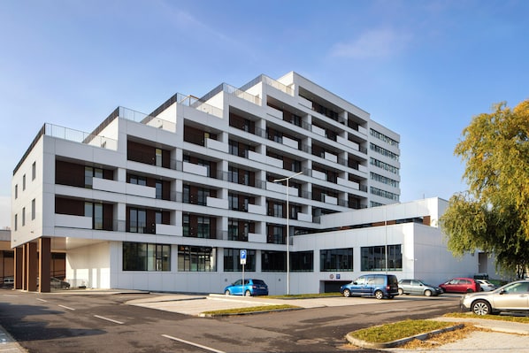 A multi-story building with a modern architectural design, featuring balconies and large windows.