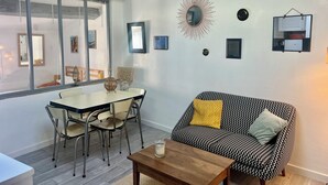 Un salon moderne comprenant un coin repas, un canapé agrémenté de coussins à motifs et un luminaire suspendu.