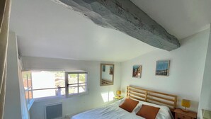 Une chambre avec un grand lit, une fenêtre, une table de chevet avec une lampe et une petite table également équipée d’une lampe.